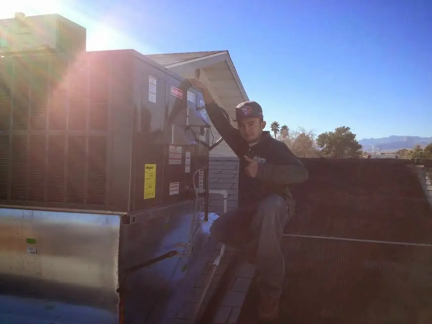 HVAC technician performing AC Tune-Up on a rooftop unit in East Providence